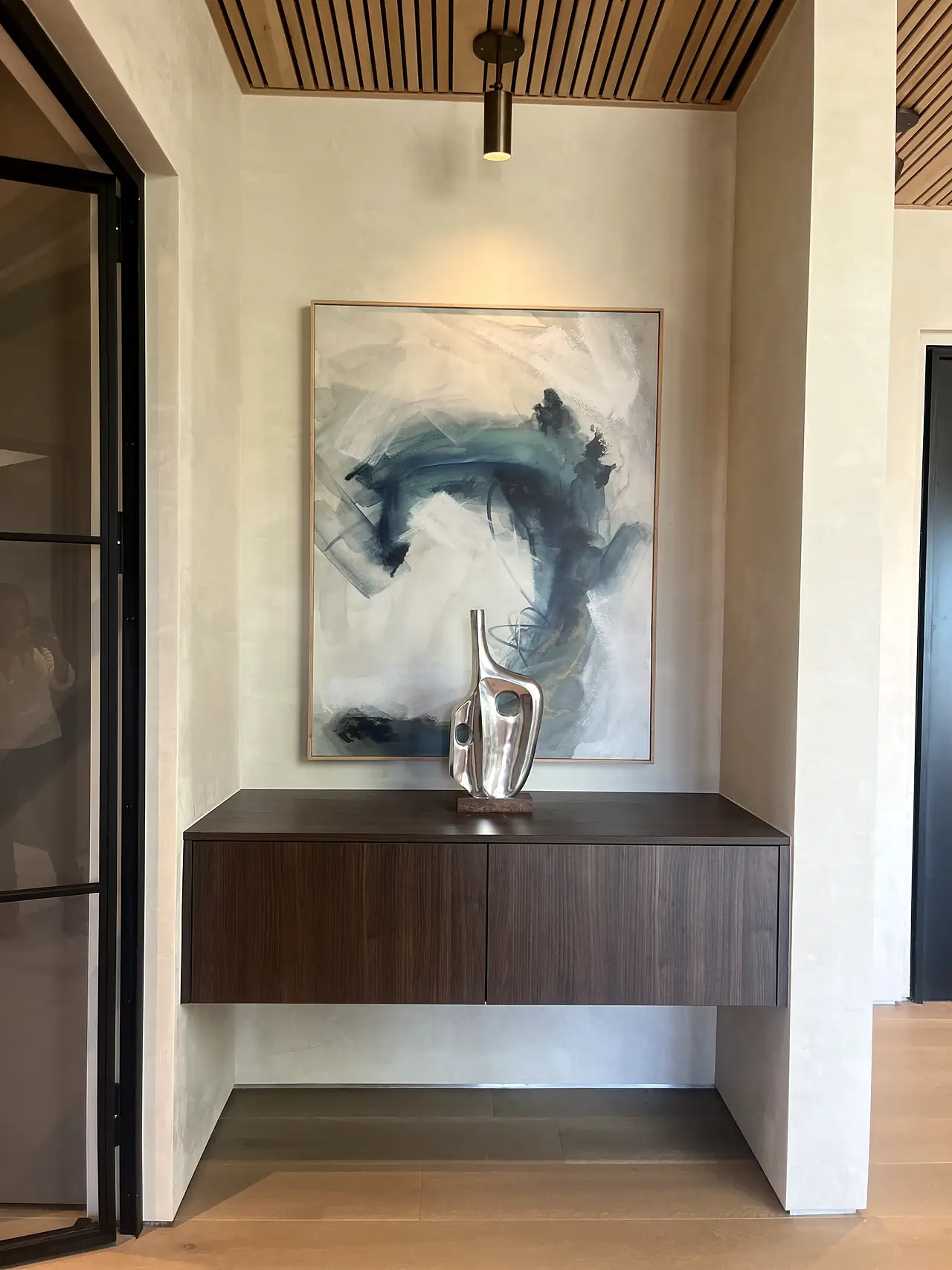 Entry niche in matte plaster with abstract artwork and a floating console