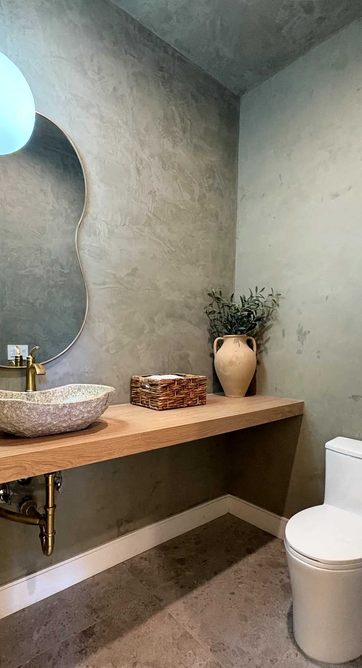 Powder room with mineral plaster walls and a stone vessel sink