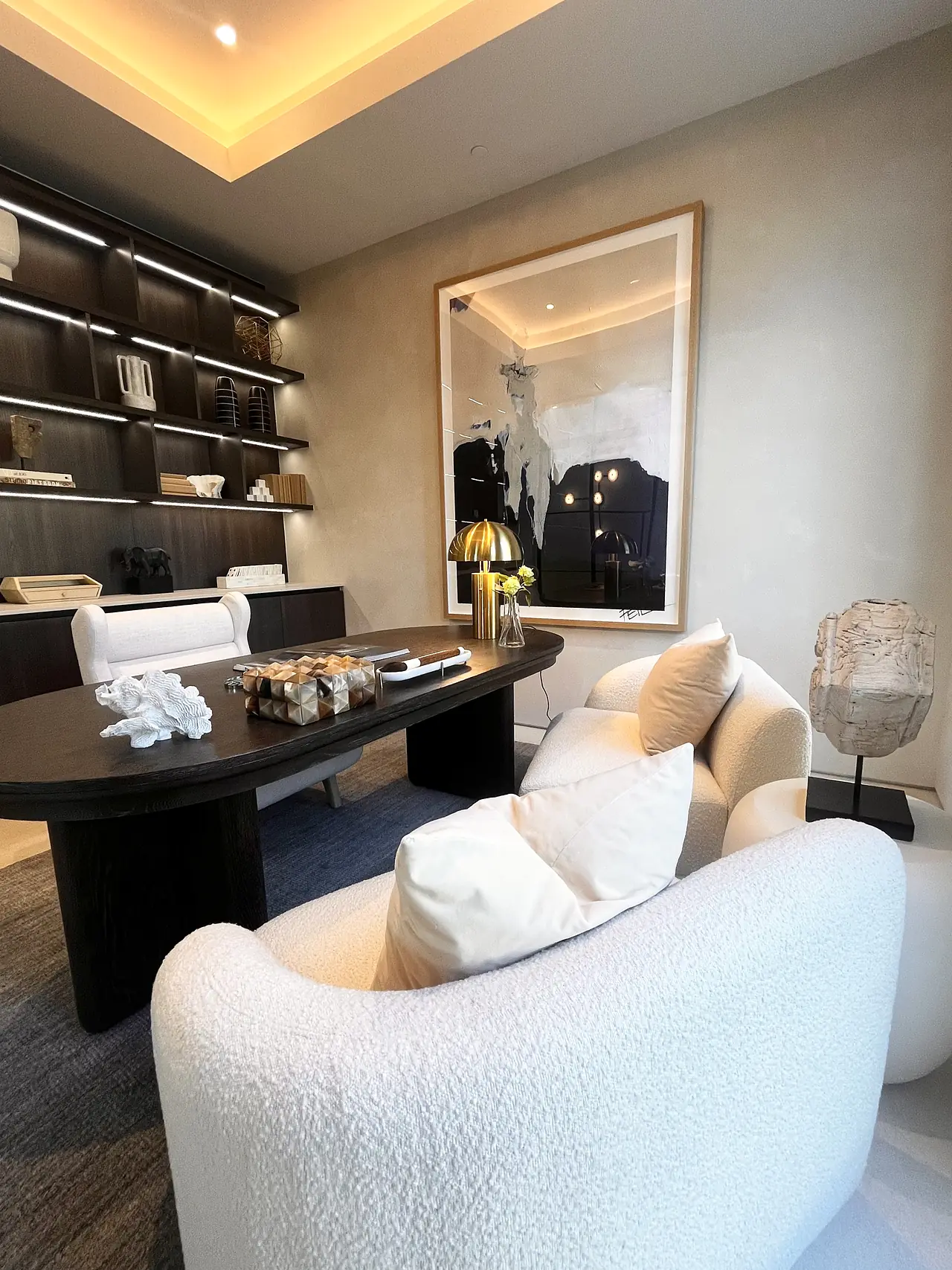 Home office with smooth plaster walls around backlit bookshelves