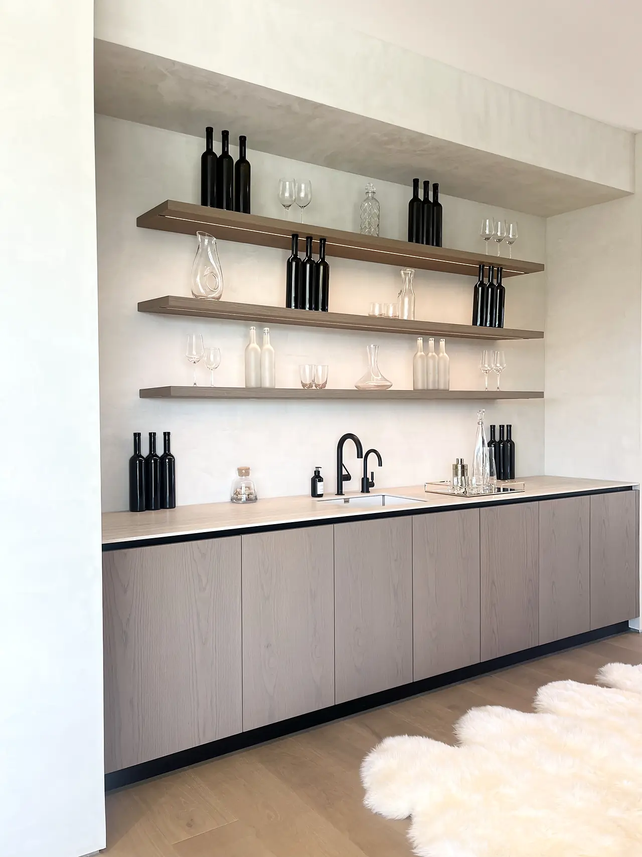 Gently textured plaster wall behind a wet bar with open oak shelves